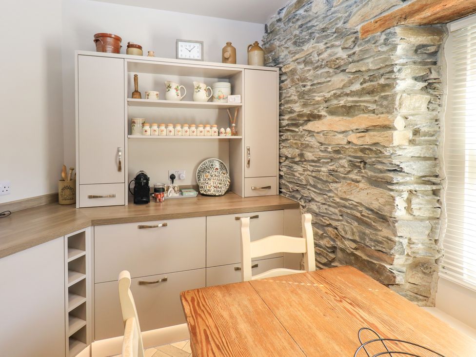 A kitchen with cabinets and a stone wall at Bridge End Cottage Haverthwaite near Cartmel