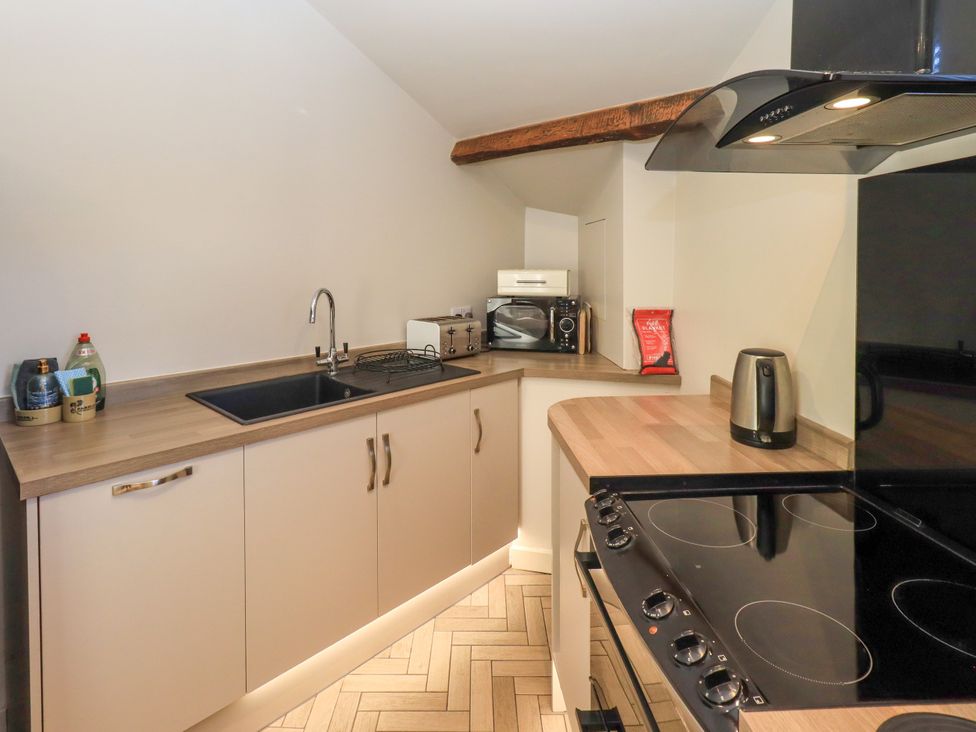 A kitchen with a sink stove kettle toaster and microwave at Bridge End Cottage in Haverthwaite near Cartmel