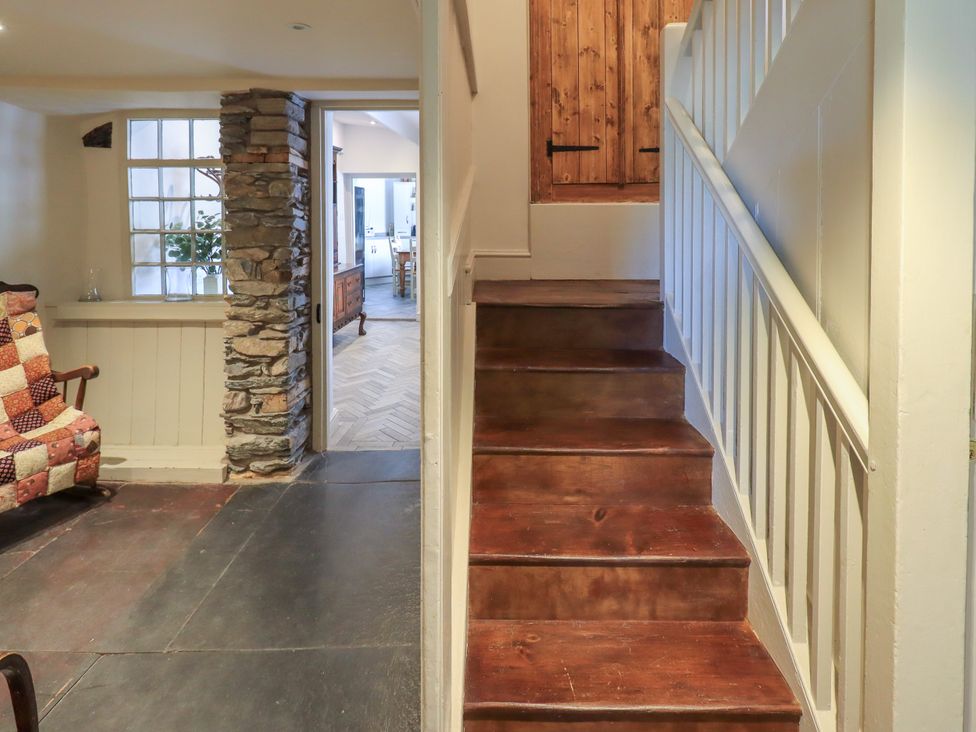 A hallway with a staircase and stone wall at Bridge End Cottage Haverthwaite near Cartmel
