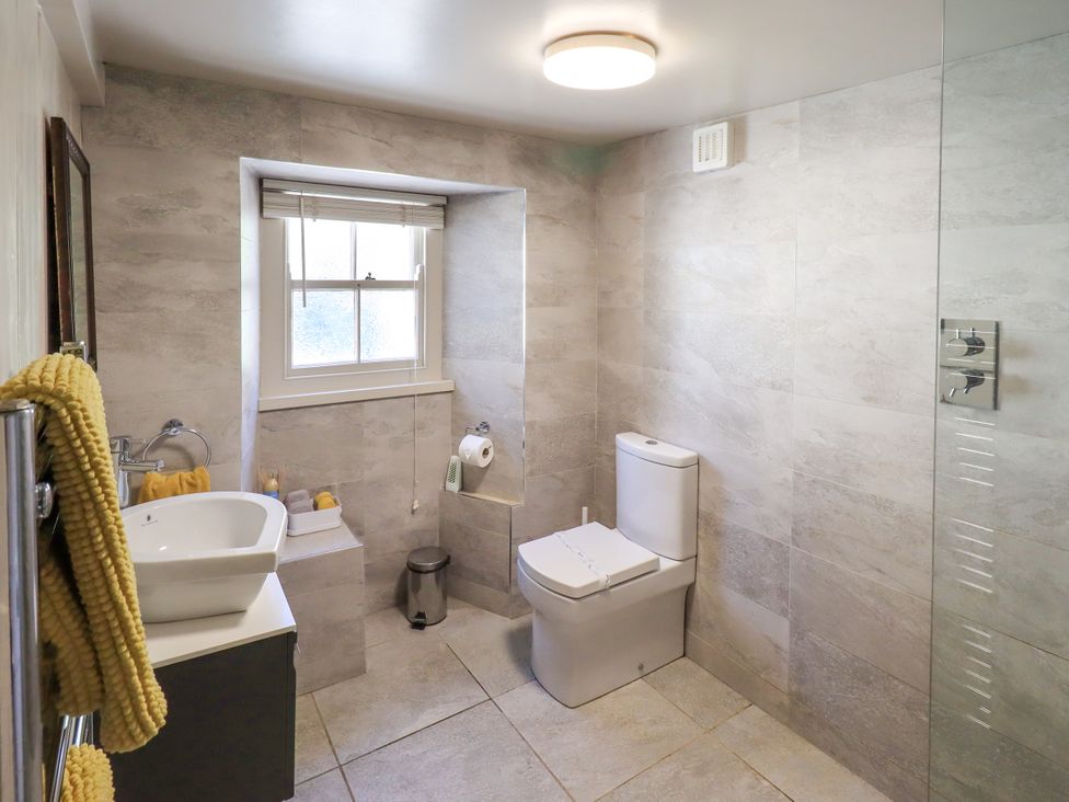 A bathroom with a sink, toilet, and shower at Bridge End Cottage in Haverthwaite near Cartmel