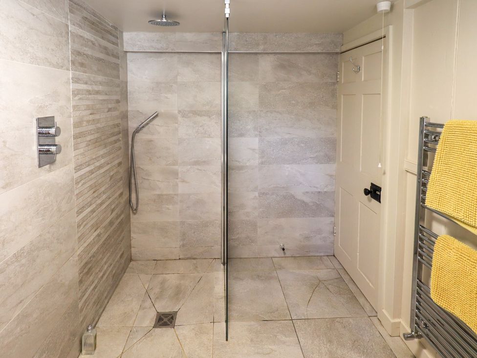 A bathroom with shower and towel rack at Bridge End Cottage Haverthwaite near Cartmel