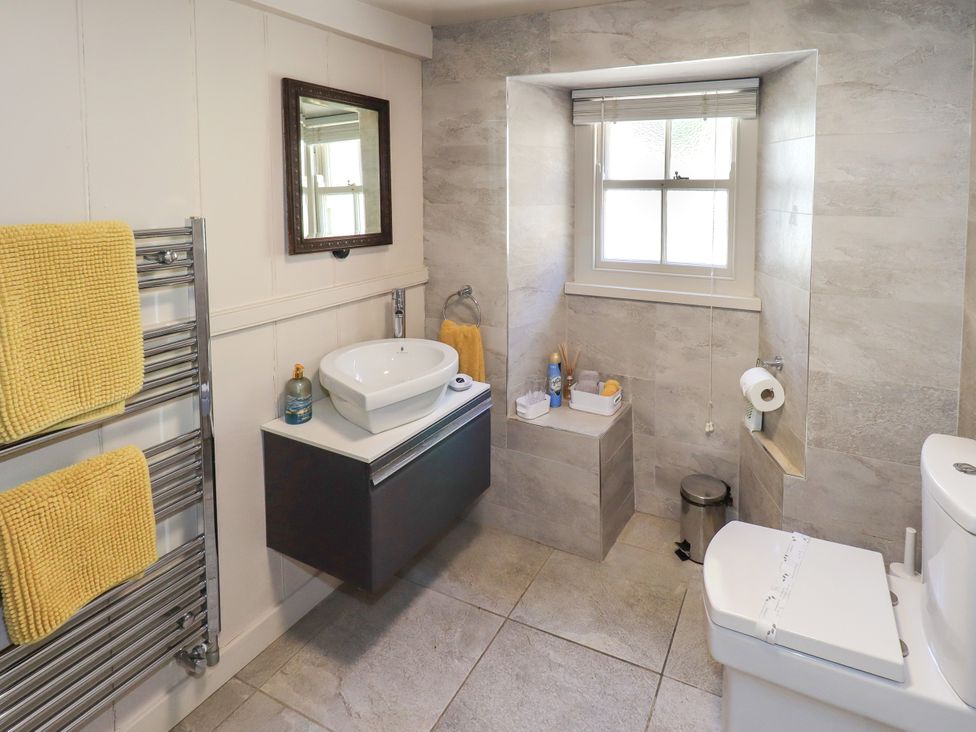 A bathroom with a sink, toilet, and towel rail at Bridge End Cottage Haverthwaite near Cartmel
