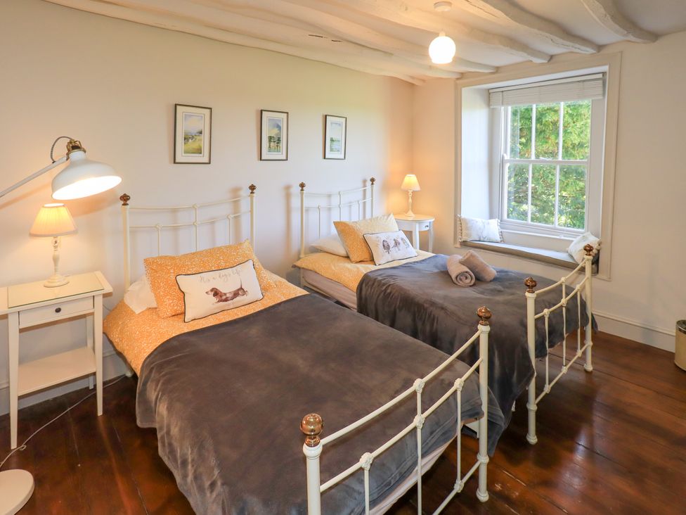 A bedroom with two beds and a window at Bridge End Cottage Haverthwaite near Cartmel