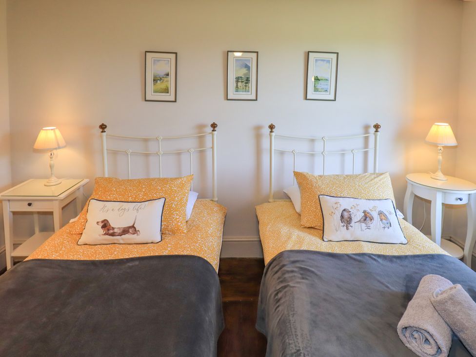 A bedroom with two beds and nightstands at Bridge End Cottage in Haverthwaite near Cartmel