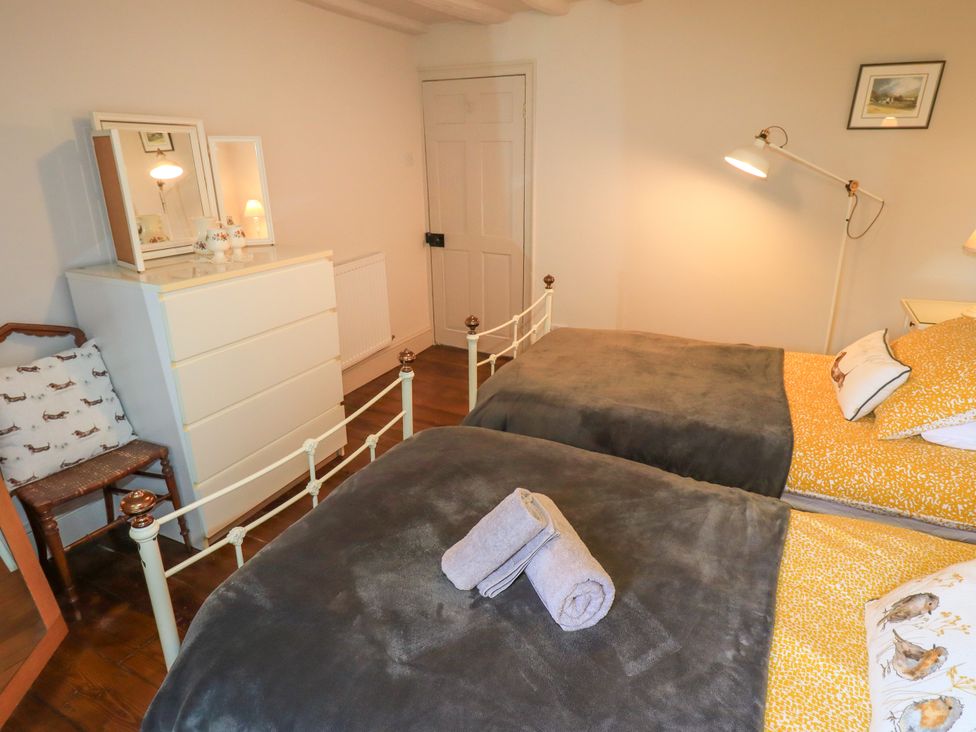 A bedroom with two beds and a dresser at Bridge End Cottage Haverthwaite near Cartmel