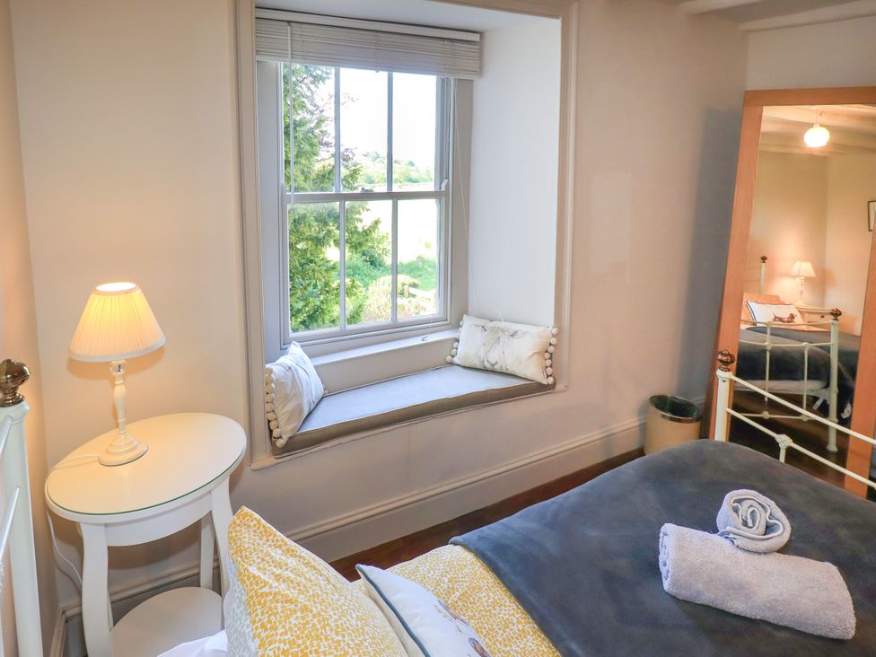 A bedroom with a window seat and a mirror at Bridge End Cottage in Haverthwaite near Cartmel