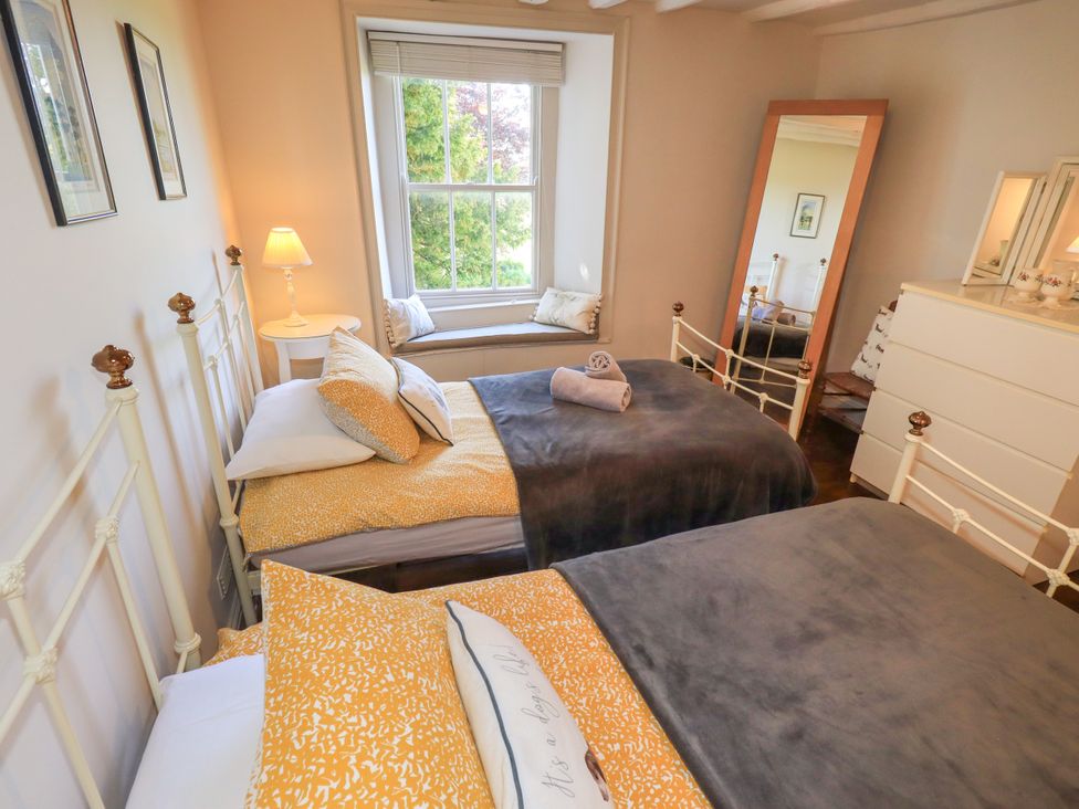 A bedroom with two beds and a window seat at Bridge End Cottage in Haverthwaite near Cartmel
