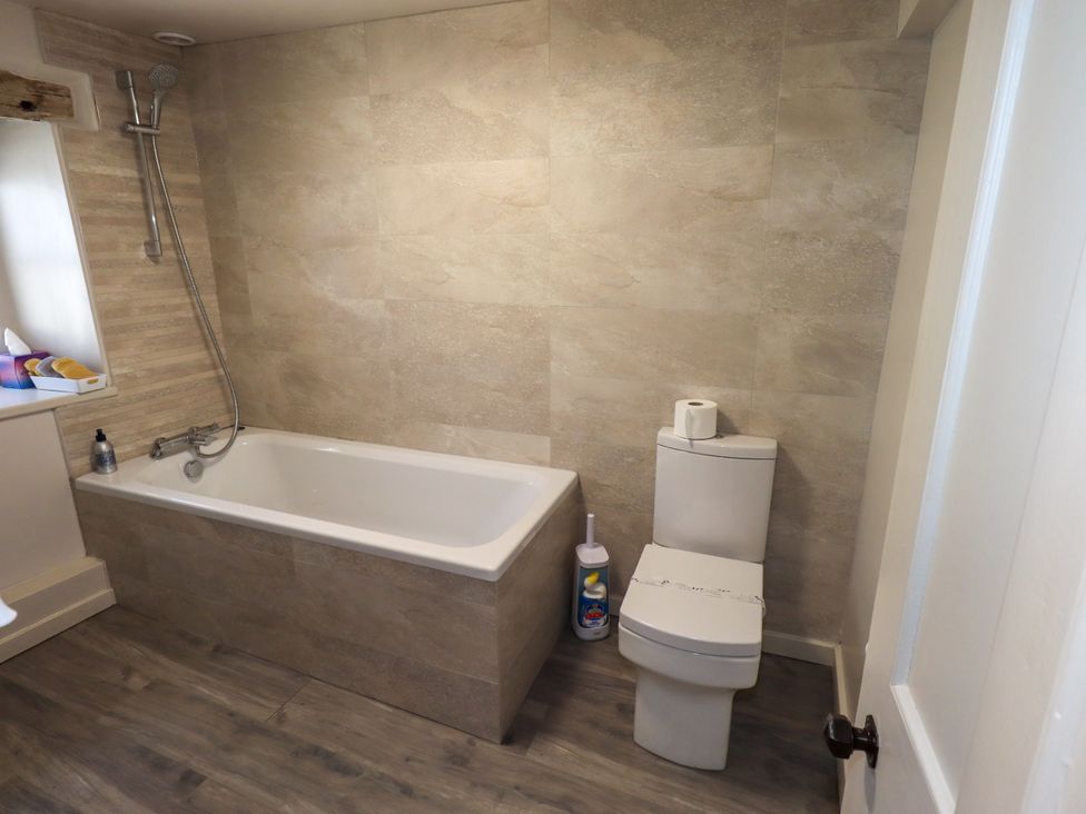 A bathroom with a bathtub and toilet at Bridge End Cottage Haverthwaite near Cartmel