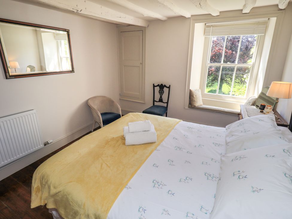 A bedroom with a bed and chairs at Bridge End Cottage Haverthwaite near Cartmel