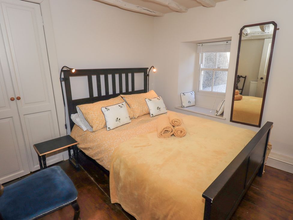 A bedroom with a bed, pillows, and a mirror at Bridge End Cottage in Haverthwaite near Cartmel
