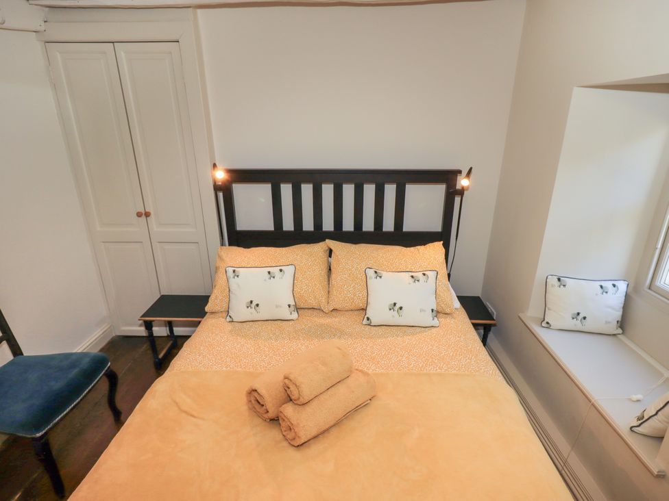 A bedroom with a bed and chair at Bridge End Cottage Haverthwaite near Cartmel