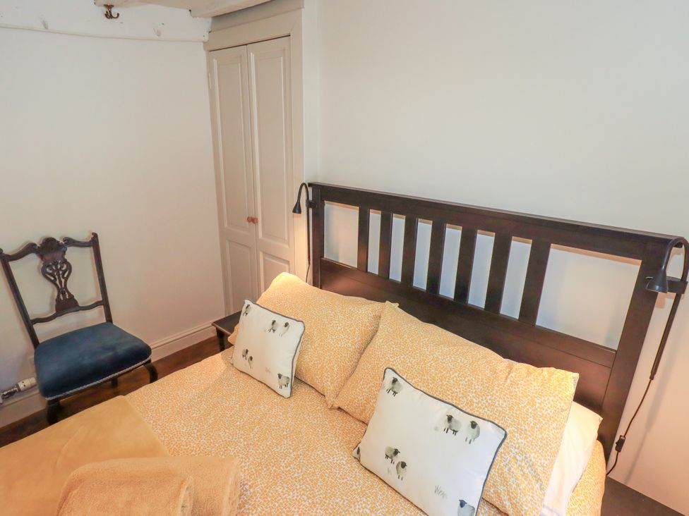 A bedroom with a bed and a chair at Bridge End Cottage Haverthwaite near Cartmel