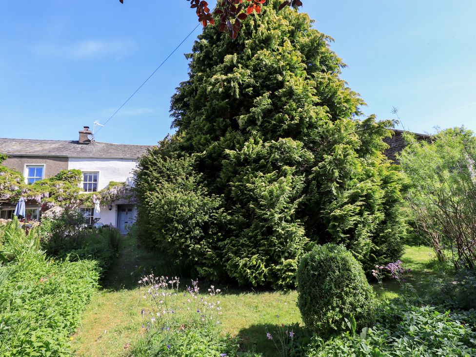 A garden with trees and a house at Bridge End Cottage Haverthwaite near Cartmel