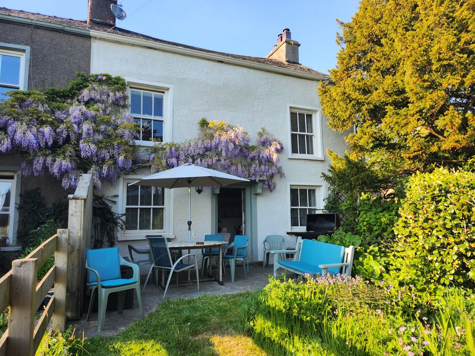 A garden with a table and chairs under an umbrella at Bridge End Cottage Haverthwaite near Cartmel