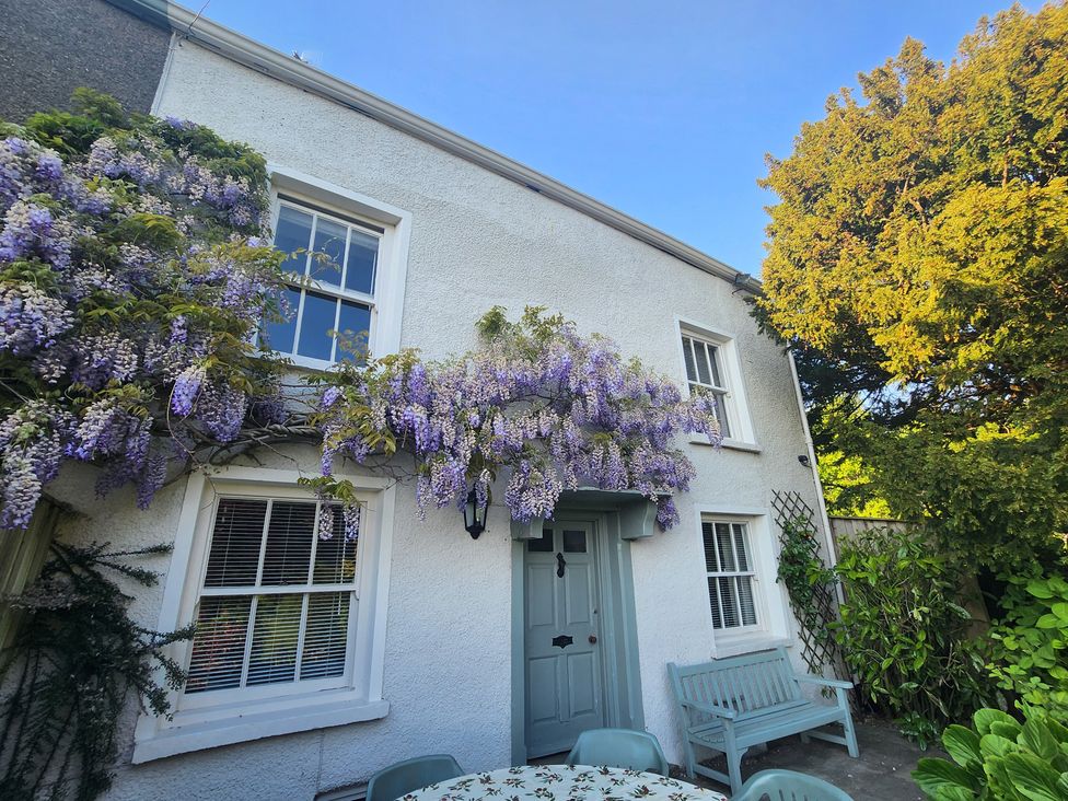 An outdoor area with a house and flowering plants at Bridge End Cottage Haverthwaite near Cartmel