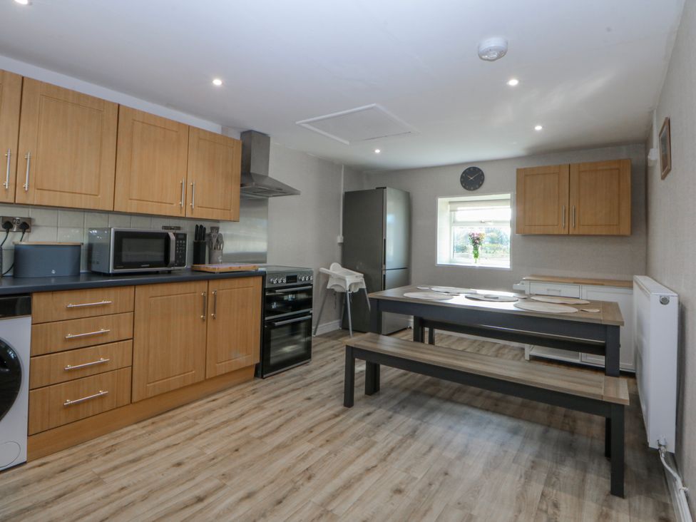 A kitchen with wooden cabinets and a table at Gate House in Capel Coch near Llanerchymedd