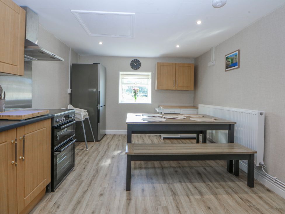 A kitchen with appliances and a dining table at Gate House Capel Coch near Llanerchymedd