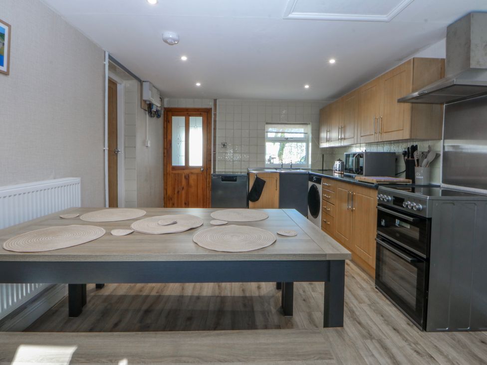 A kitchen with a table and kitchen appliances at Gate House Capel Coch near Llanerchymedd