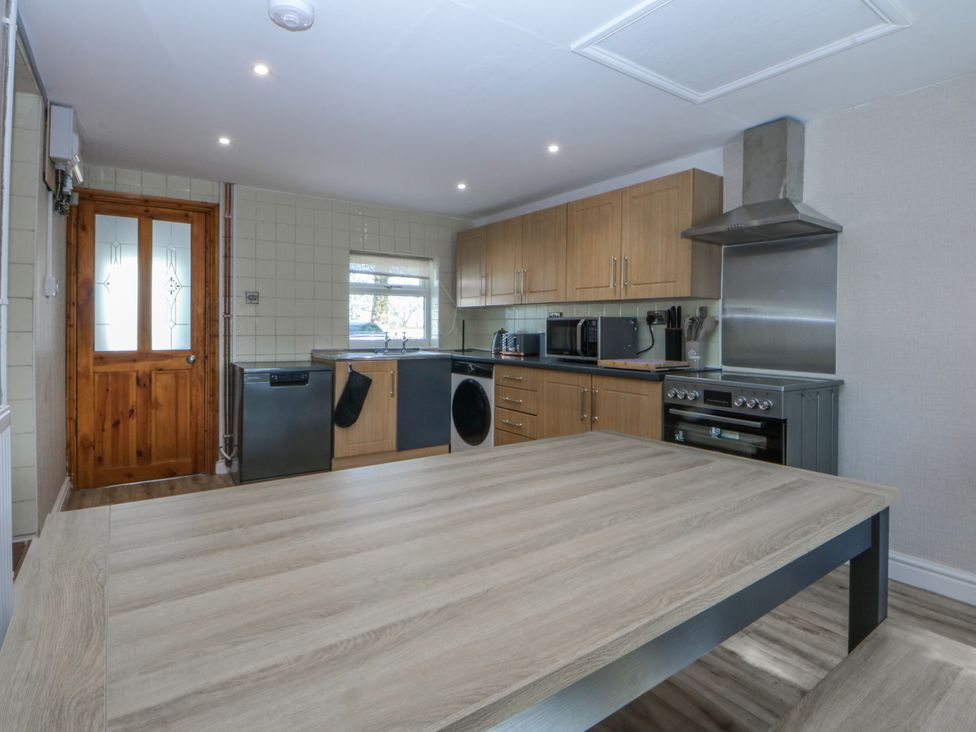 A kitchen with appliances and a table at Gate House Capel Coch near Llanerchymedd