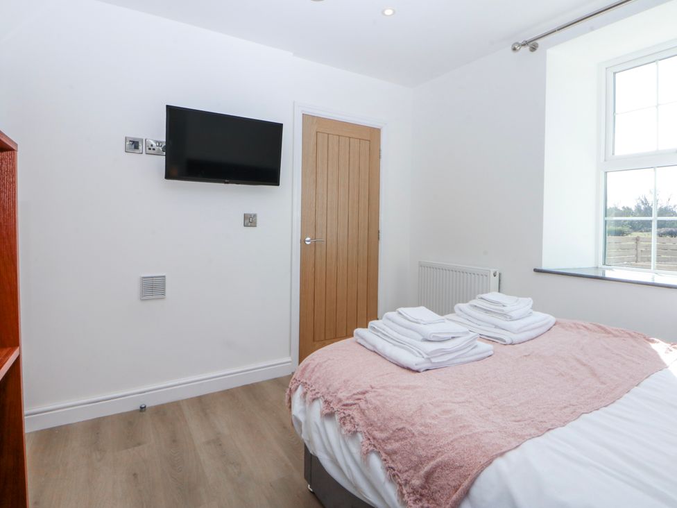 A bedroom with a bed and television at Gate House Capel Coch near Llanerchymedd