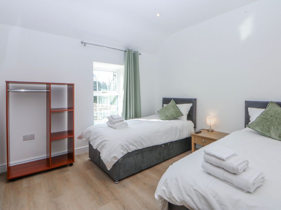 A bedroom with two beds and a shelf at Gate House Capel Coch near Llanerchymedd