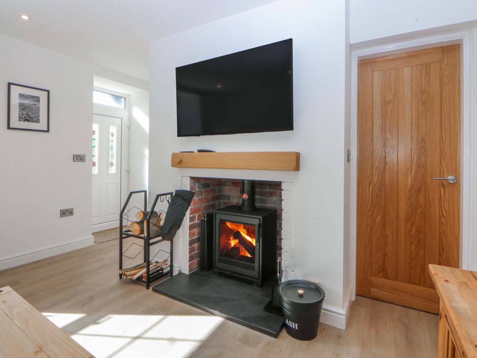 A living room with a fireplace and TV at Gate House Capel Coch near Llanerchymedd