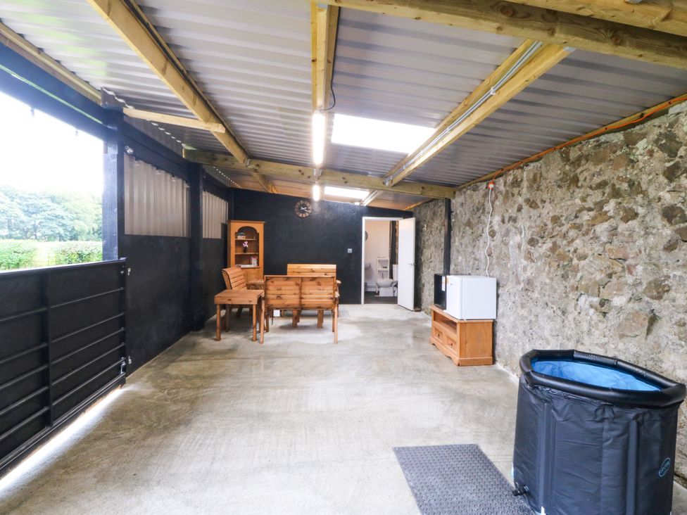 An indoor patio with a table and chairs at Gate House Capel Coch near Llanerchymedd