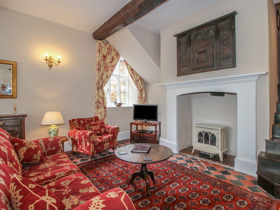 A living room with a sofa, armchair, coffee table, and television at The Butler’s Quarters in Bourton near Much Wenlock