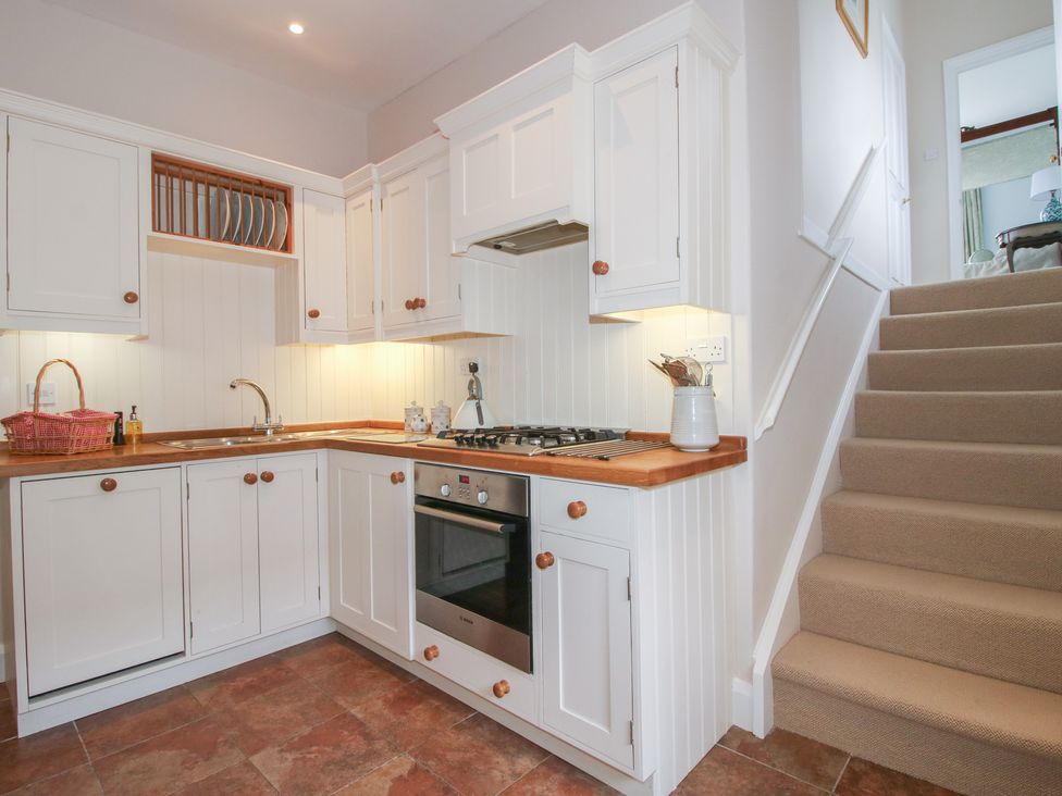 A kitchen with cabinets, sink, stove, and stairs at The Butler’s Quarters in Bourton near Much Wenlock