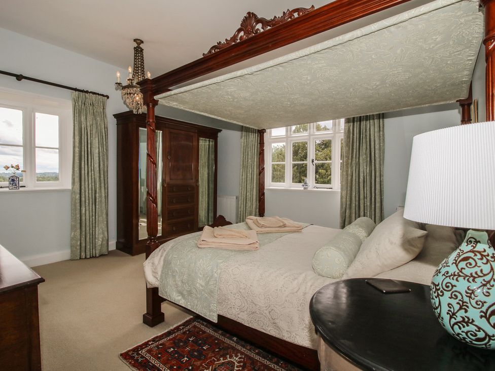 A bedroom with a four-poster bed and wardrobe at The Butler’s Quarters in Bourton near Much Wenlock