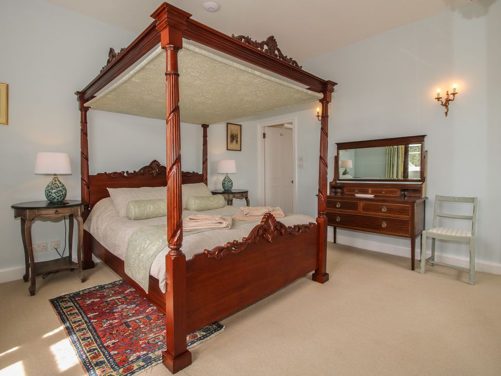 A bedroom with a four-poster bed and dressing table at The Butler’s Quarters in Bourton near Much Wenlock