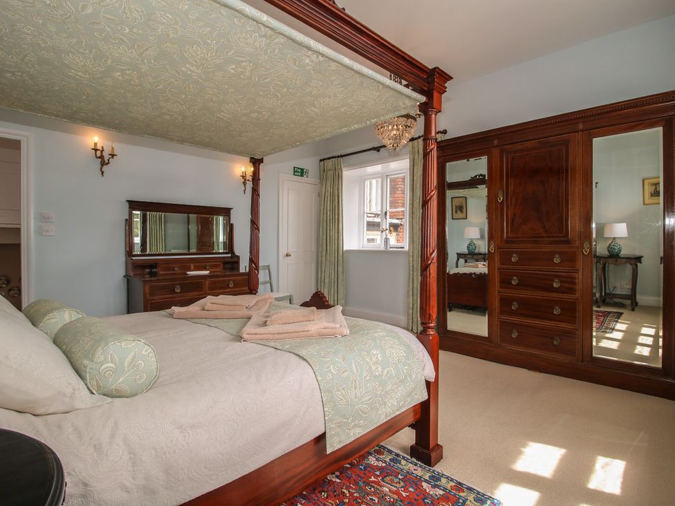 A bedroom with a four-poster bed and a dressing table at The Butler’s Quarters in Bourton near Much Wenlock