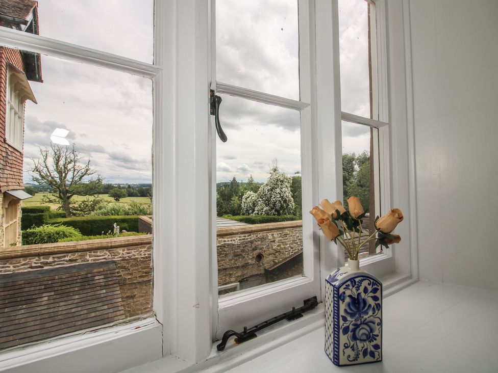 A window with flowers in a vase overlooking a field at The Butler’s Quarters Bourton near Much Wenlock