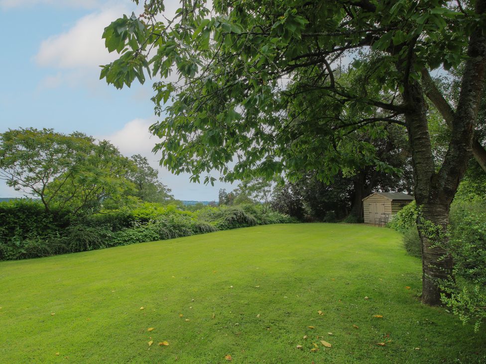 A garden with grass and trees at The Butler’s Quarters in Bourton near Much Wenlock
