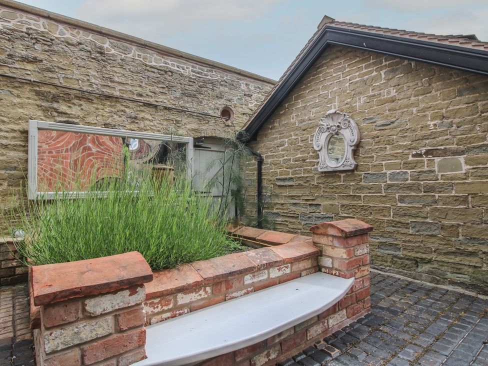 An outdoor area with a planter and a mirror on the wall at The Butler’s Quarters in Bourton near Much Wenlock