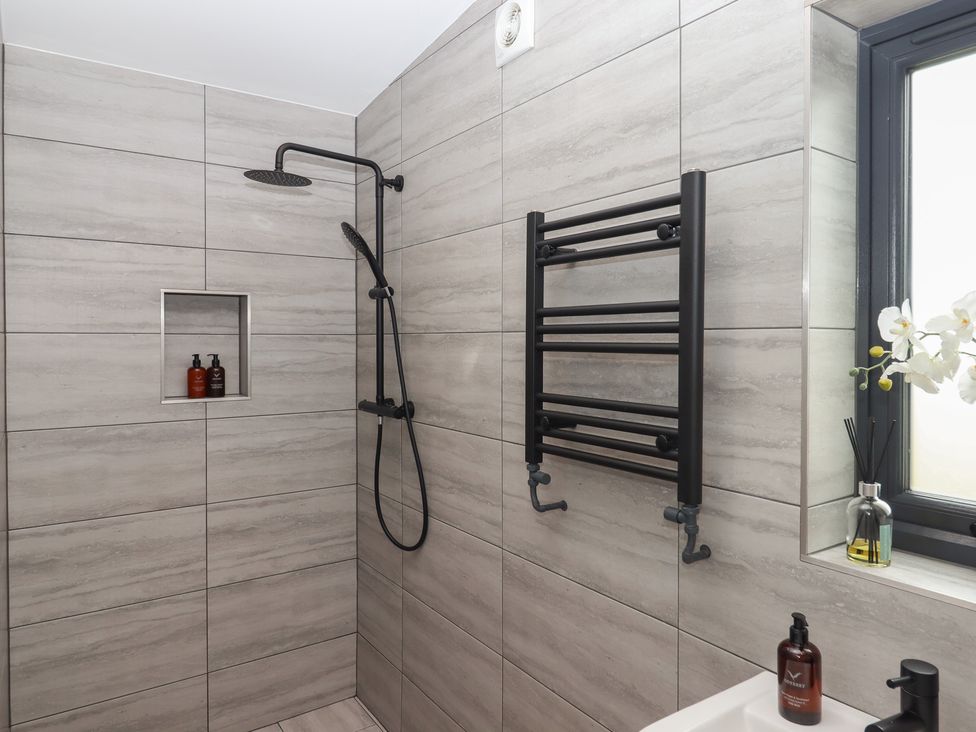 A bathroom with a shower, towel rail and soap dispenser at The Cadeleigh near Tiverton
