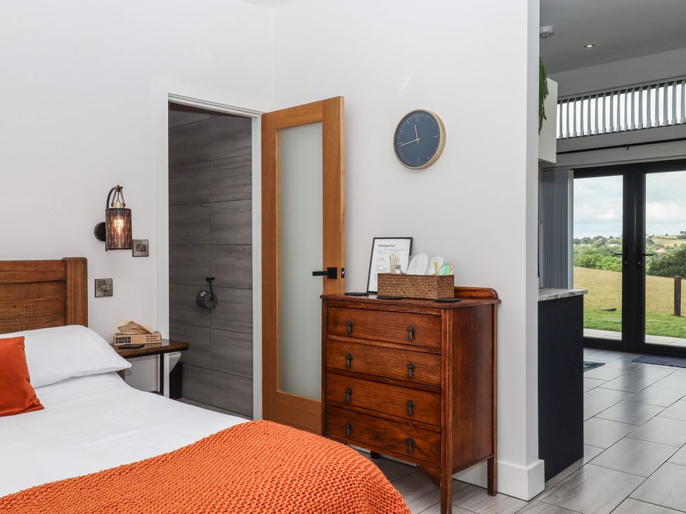 A bedroom with a bed and wooden furniture at The Cadeleigh near Tiverton