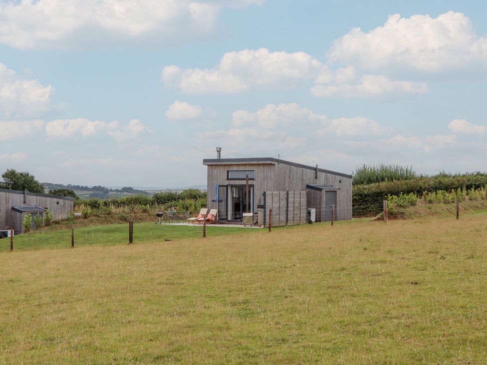 A house with a deck and chairs in a grassy area at The Cadeleigh near Tiverton