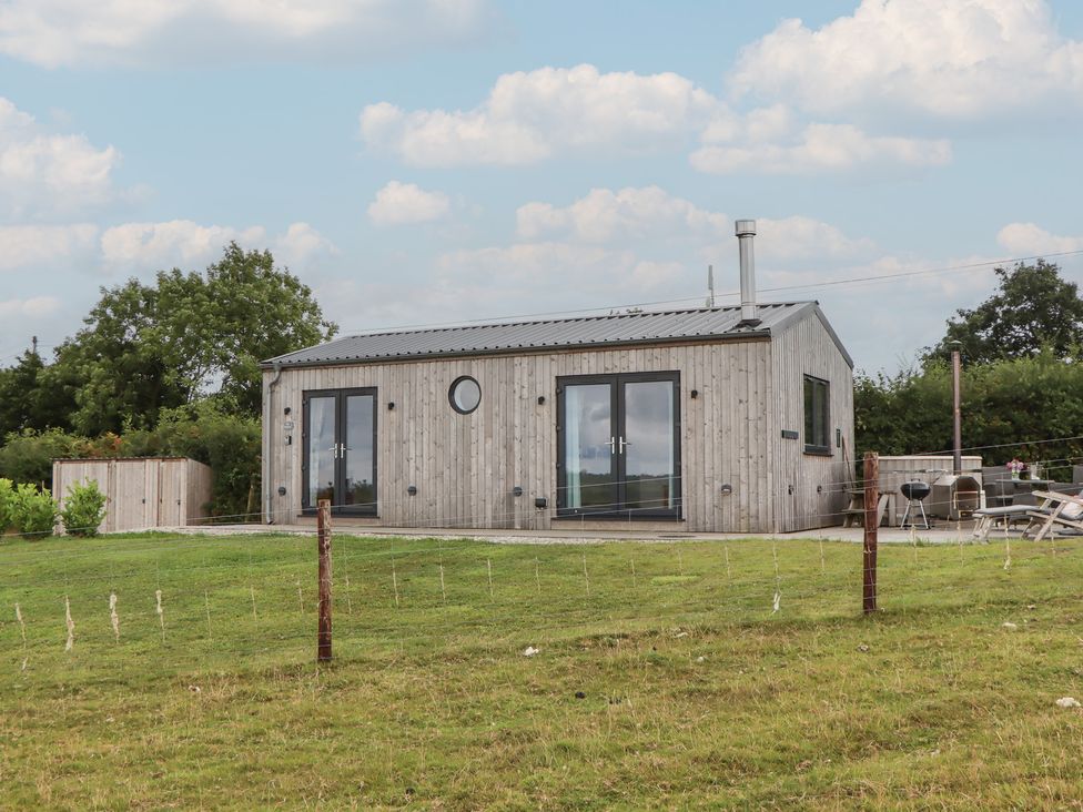 A house with wooden exterior and patio furniture at The Pennymoor Cadeleigh near Tiverton