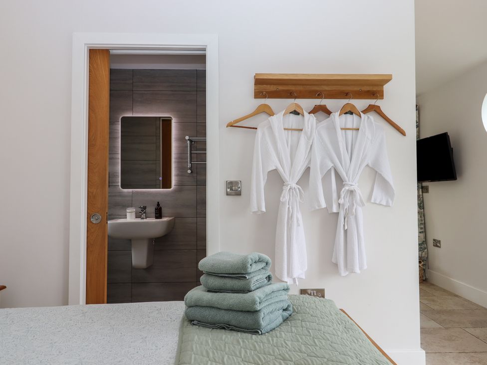 A bedroom with a bed and bathrobes hanging at The Pennymoor in Cadeleigh near Tiverton