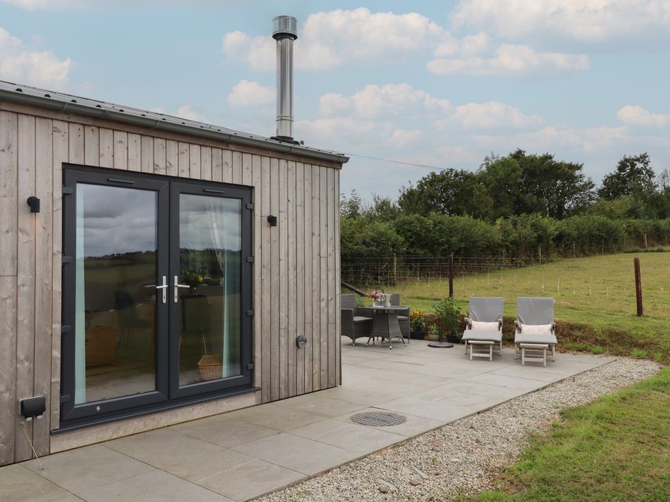 An outdoor area with a wooden building and patio furniture at The Pennymoor in Cadeleigh near Tiverton