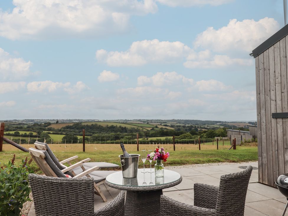 A seating area with a table and chairs overlooking the countryside at The Pennymoor in Cadeleigh near Tiverton