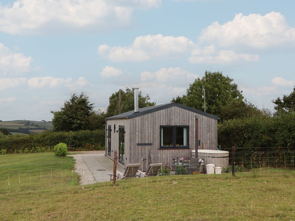 A wooden house with a pathway and grass area at The Pennymoor Cadeleigh near Tiverton