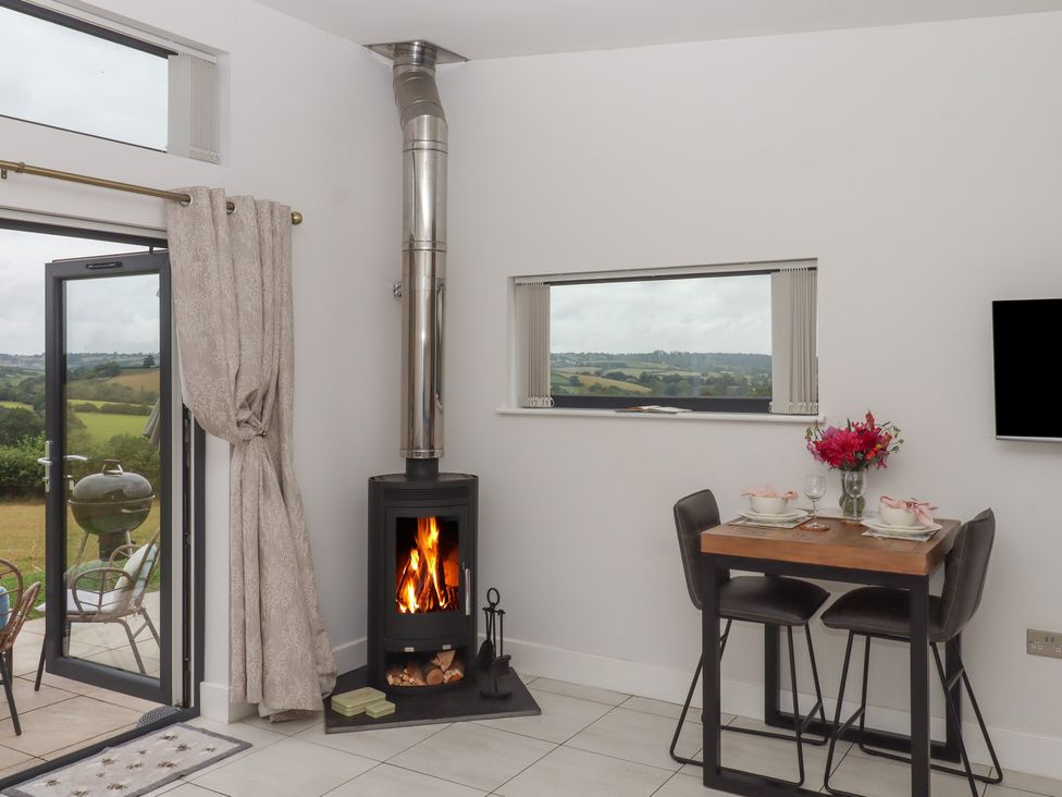 A dining area with a wood stove and table at The Bickleigh in Cadeleigh near Tiverton