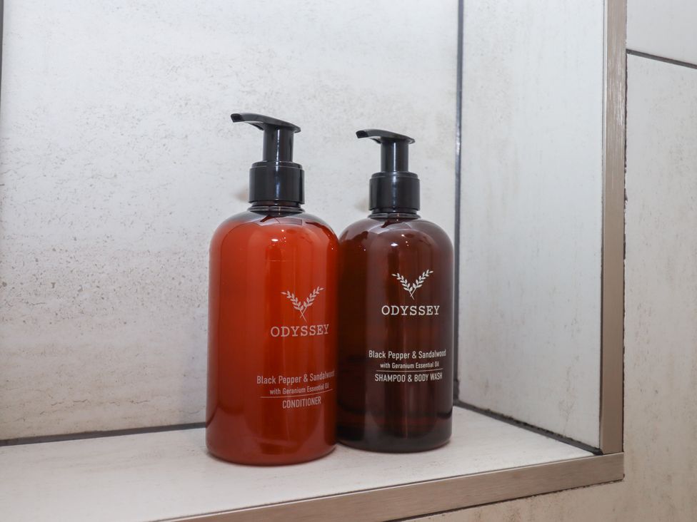 Bottles of conditioner and shampoo on a shelf in a bathroom at The Bickleigh Cadeleigh near Tiverton