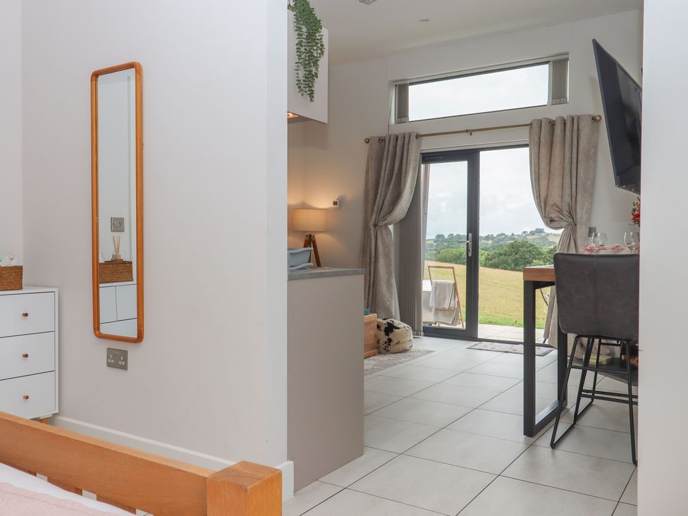 A living room with a mirror and a view of the outdoors at The Bickleigh Cadeleigh near Tiverton