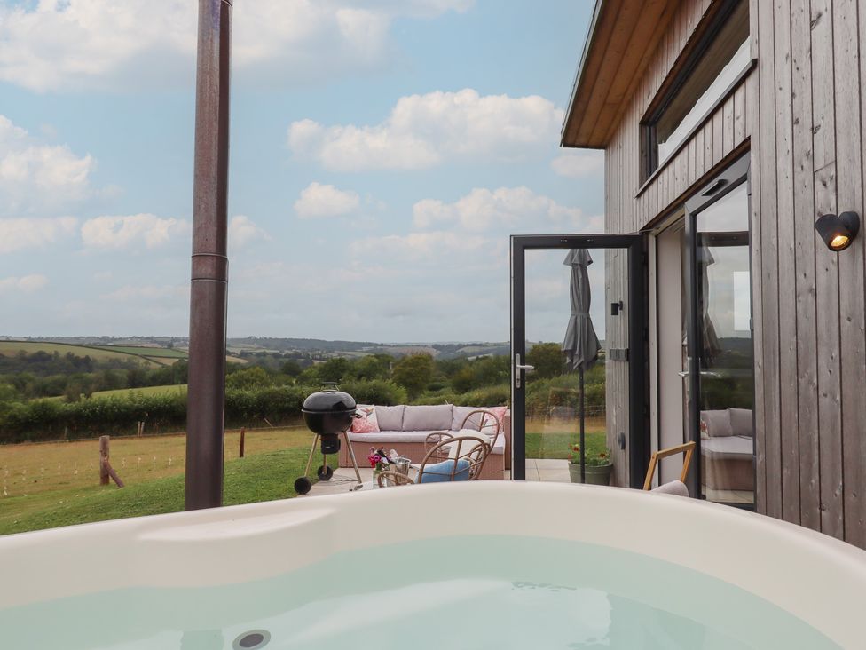 An outdoor area with a hot tub and seating at The Bickleigh in Cadeleigh near Tiverton