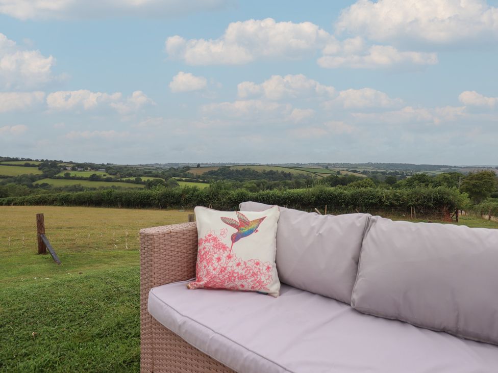 A couch with a pillow overlooking a landscape at The Bickleigh in Cadeleigh near Tiverton