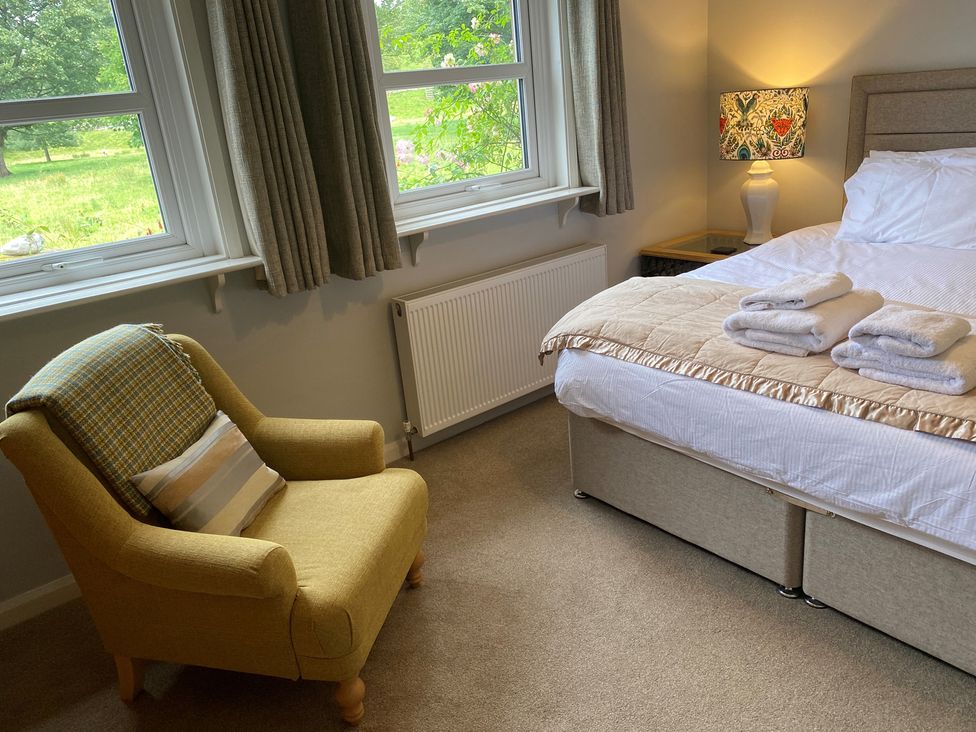 A bedroom with a bed, towels, a lamp, and a chair at Greywalls in Maulds Meaburn