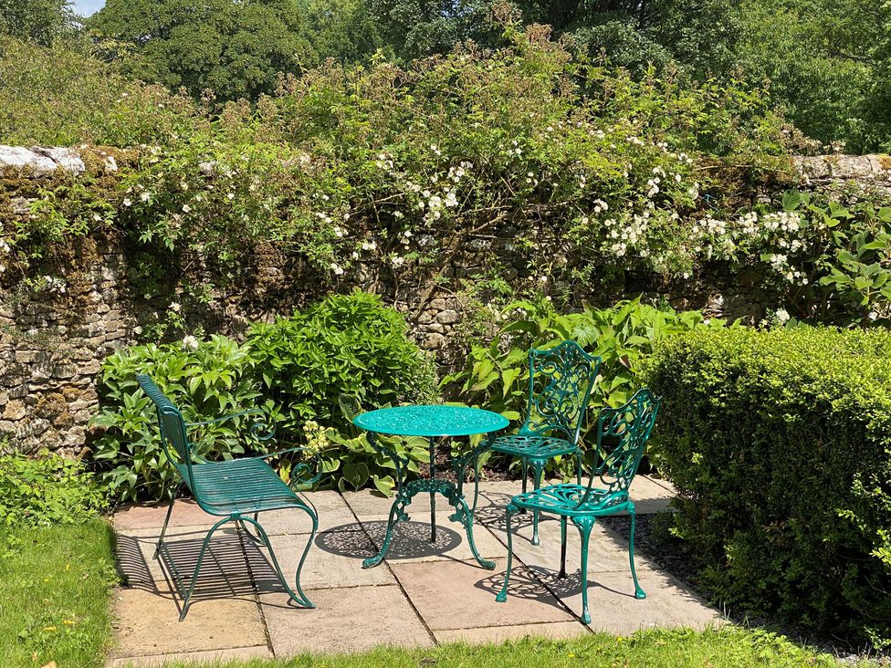 A garden with a table and chairs surrounded by plants at Greywalls in Maulds Meaburn